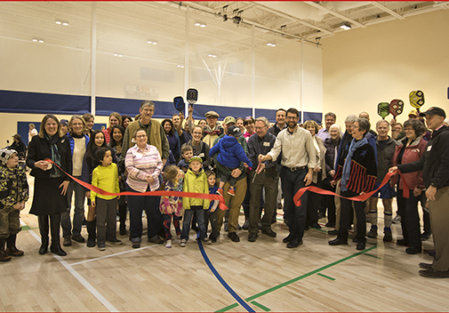 Members of the Middlebury Selectboard, Parks & Recreation Committee, Town Offices & Recreation Facilities Building Committee and residents celebrate the grand opening of Middlebury’s new Recreation Center with an official ribbon cutting. Kathleen Ramsay, Middlebury Town Manager (L) and David Donahue, Special Assistant to the President of Middlebury College (R) hold ribbon cut by Nick Artim of the Middlebury Selectboard (L) and Chris Huston, Architect from Bread Loaf Corporation (R).